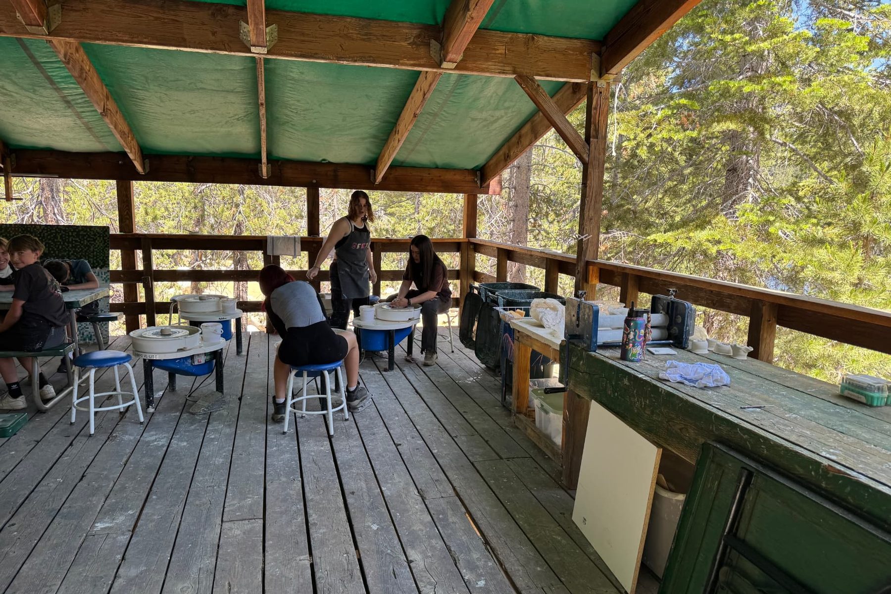Campers working at pottery wheels on an open-air deck
